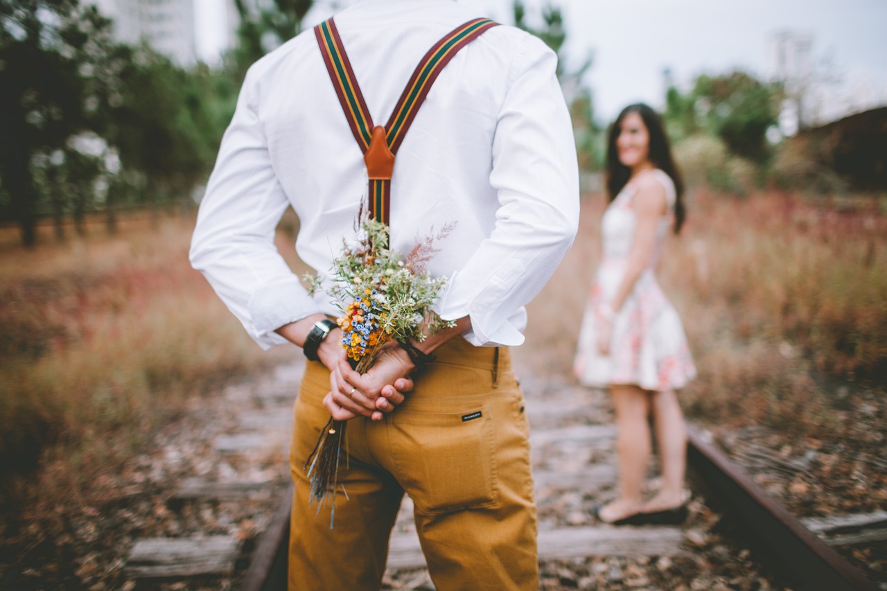 Homme romantique tenant un bouquet de fleurs derrière son dos